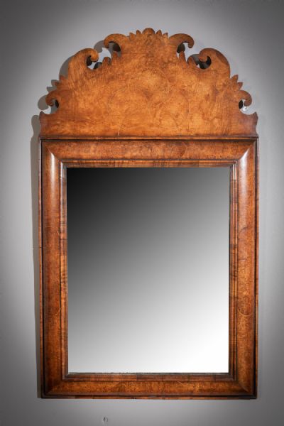 A WALNUT CUSHIONED WALL MIRROR at deVeres Auctions