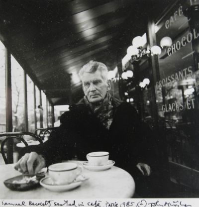 SAMUEL BECKETT SEATED IN A CAFE, PARIS 1985 by John Minihan  at deVeres Auctions